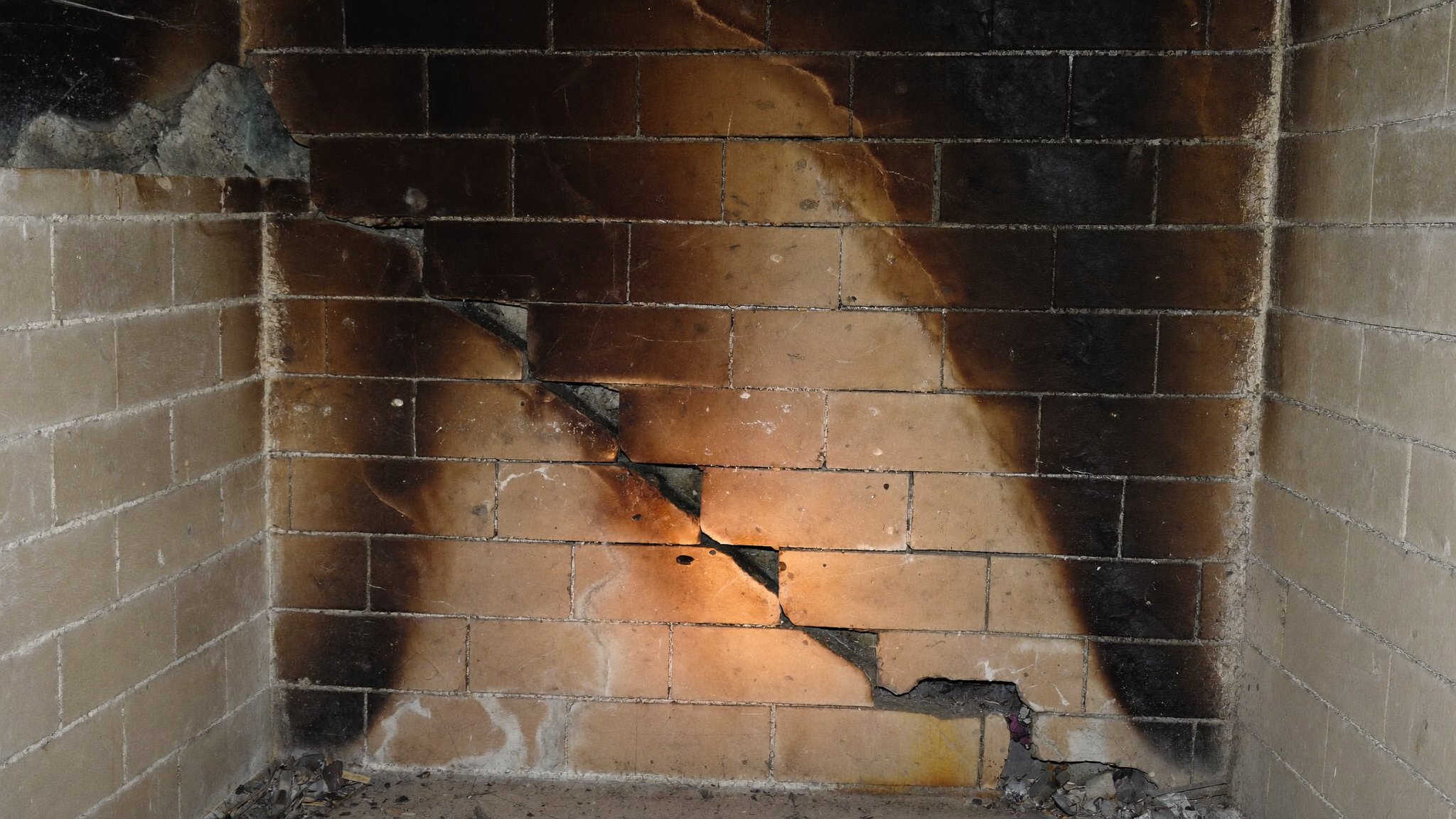 Stepped crack and missing mortar across a firebox back wall, the kind of damage that raises firebox repair cost in Dallas homes